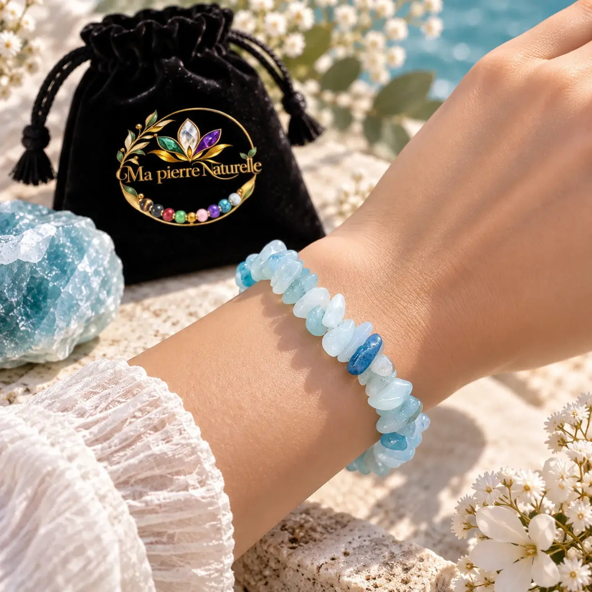 Bracelet en aigue-marine bleu pâle porté au poignet avec une manche blanche et une pochette noire en arrière-plan