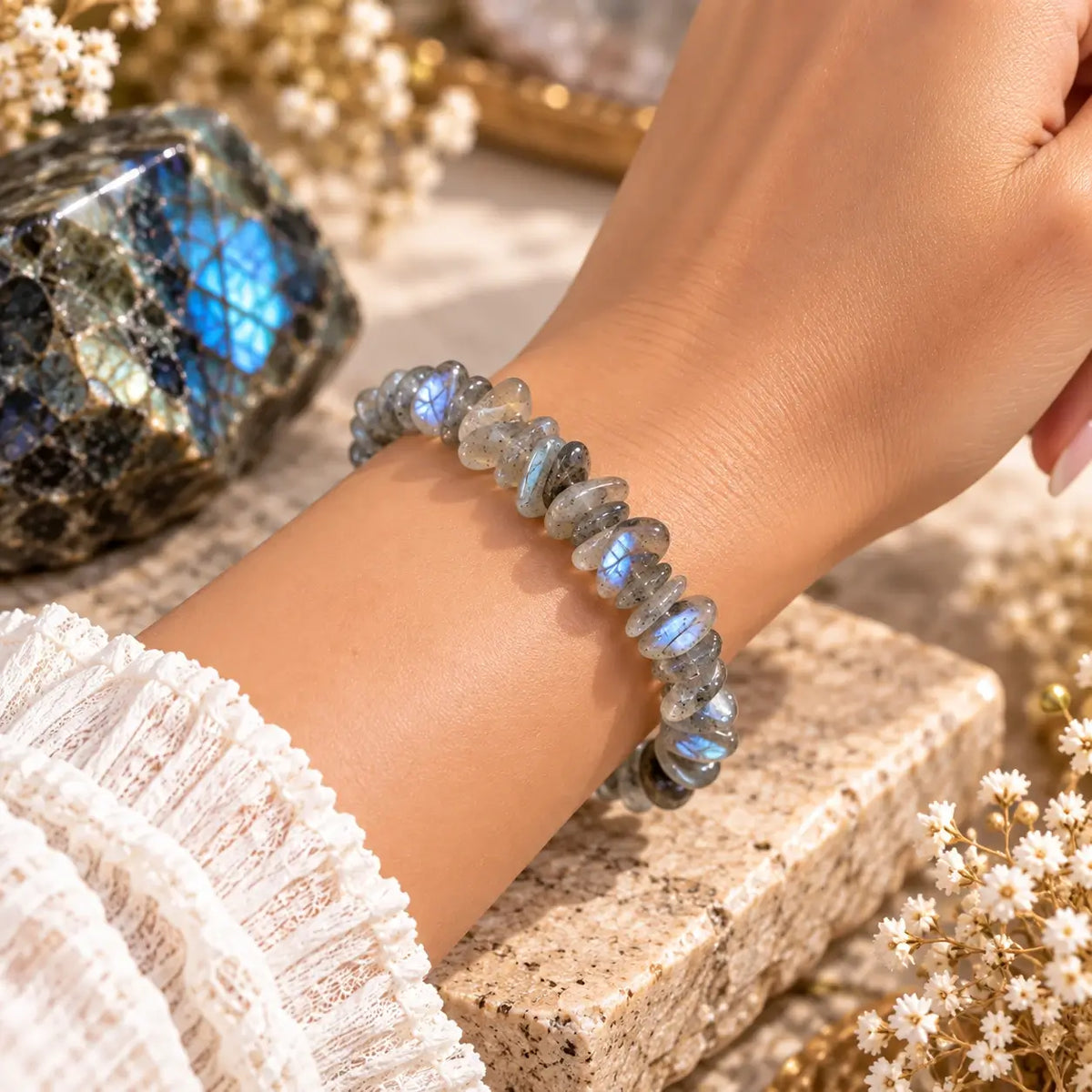 Bracelet en labradorite grise à reflets bleutés porté au poignet avec une manche claire