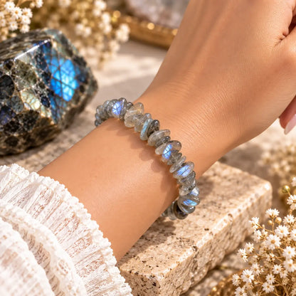Bracelet en labradorite grise à reflets bleutés porté au poignet avec une manche claire