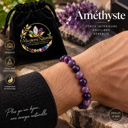 Bracelet en améthyste de 8 mm porté au poignet avec une manche foncée, à côté d’une pochette noire.