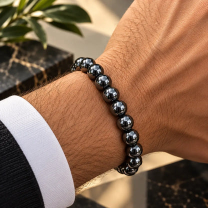 Bracelet en hématite gris anthracite de 8 mm porté au poignet avec une manche foncée.