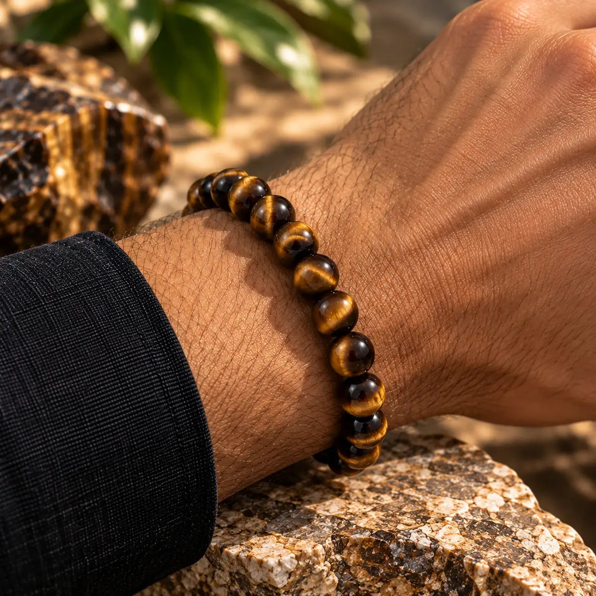 Bracelet en œil de tigre de 8 mm aux reflets bruns et dorés, porté avec une manche foncée.