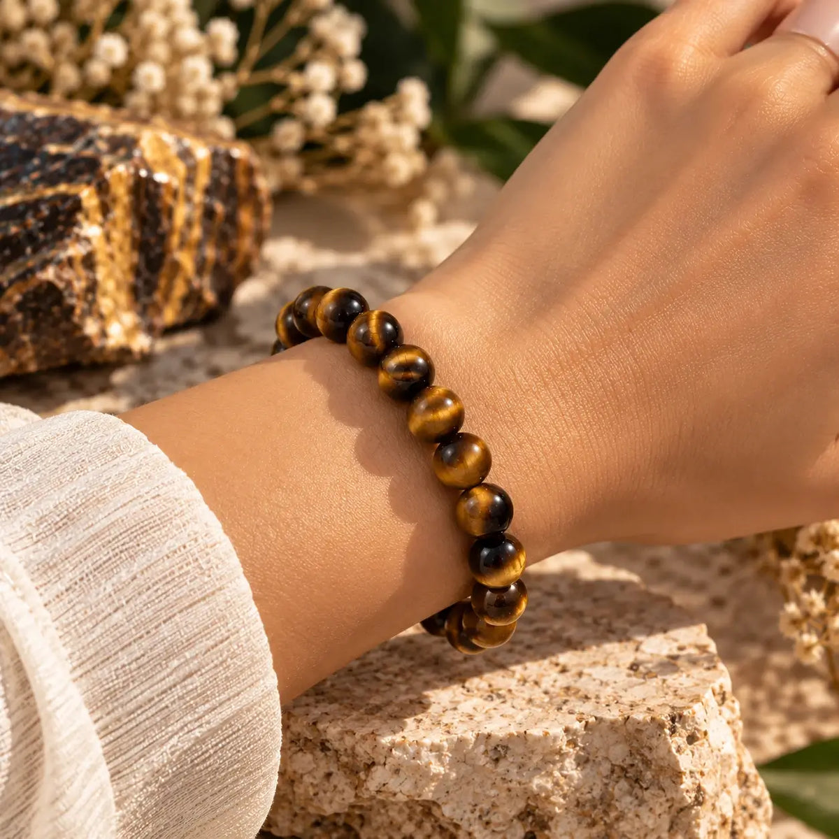 Bracelet en œil de tigre à perles rondes de 8 mm porté au poignet avec une manche claire.