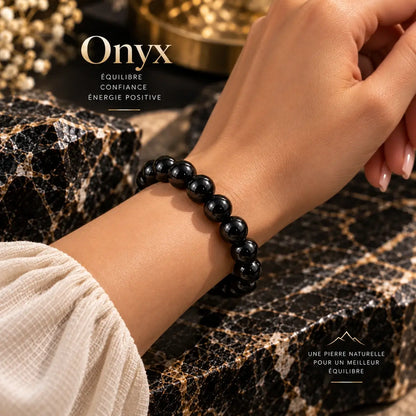 Bracelet en onyx noir à perles rondes de 8 mm porté au poignet avec une manche claire.
