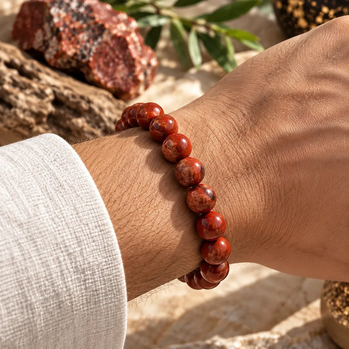 Bracelet en jaspe rouge de 8 mm porté au poignet avec une manche blanche.