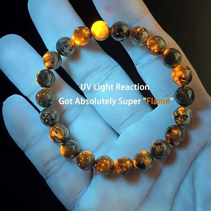 Bracelet Yooperlite tenu dans une main, avec des zones de fluorescence orange sous UV.